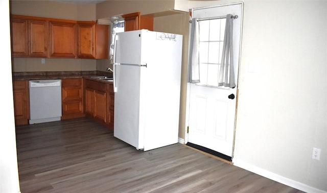 kitchen with sink, white appliances, and hardwood / wood-style flooring