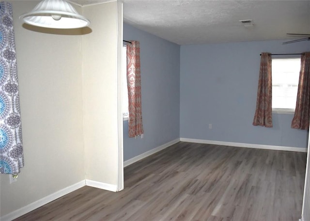 spare room with a textured ceiling and dark hardwood / wood-style floors