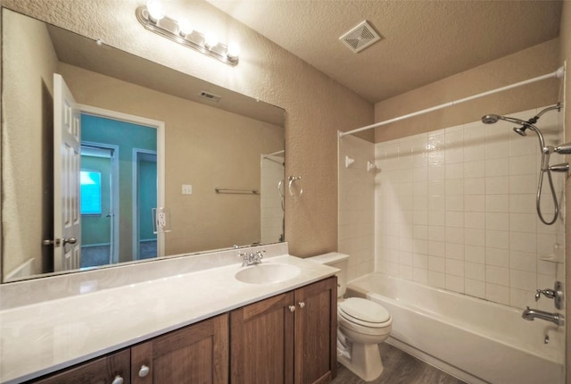 full bath with visible vents, a textured wall, toilet, a textured ceiling, and vanity