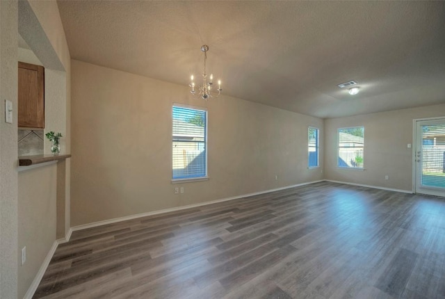 unfurnished room with visible vents, dark wood-type flooring, a textured ceiling, a chandelier, and baseboards