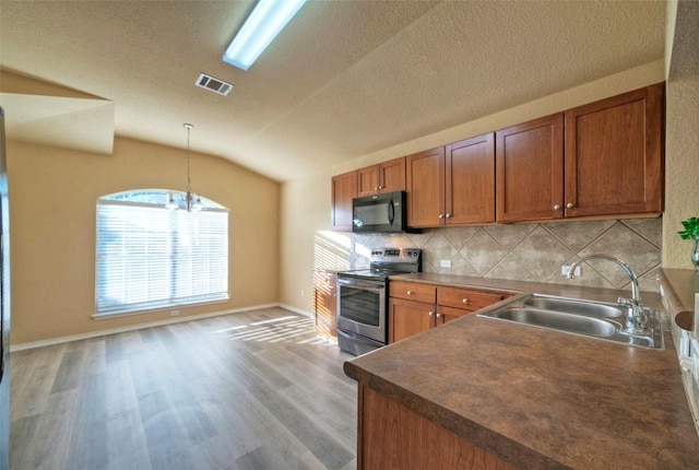 kitchen featuring visible vents, lofted ceiling, stainless steel electric stove, black microwave, and a sink