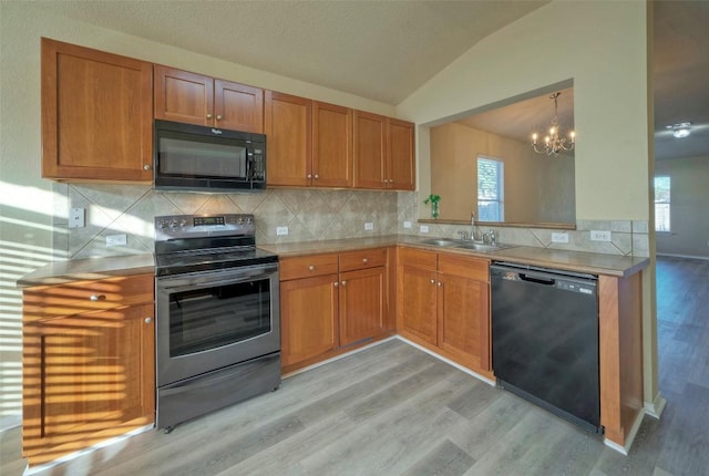 kitchen with lofted ceiling, light wood-style flooring, a sink, light countertops, and black appliances