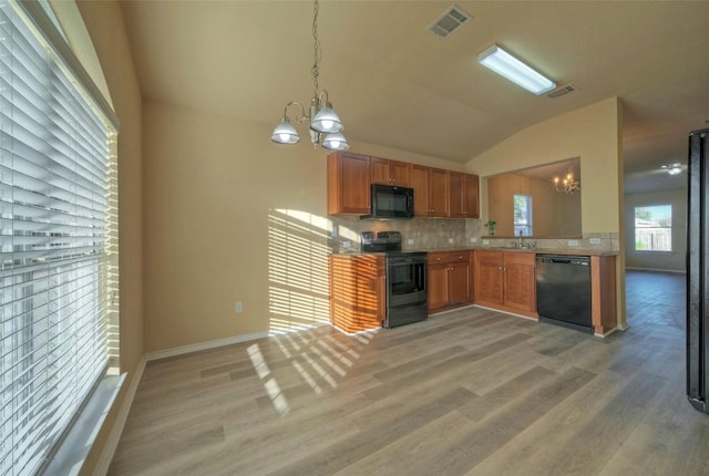 kitchen featuring a chandelier, light wood-style floors, decorative backsplash, and black appliances