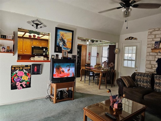 tiled living room featuring ceiling fan, a stone fireplace, and lofted ceiling