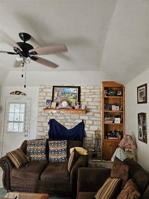 living room featuring built in shelves, ceiling fan, a textured ceiling, and vaulted ceiling