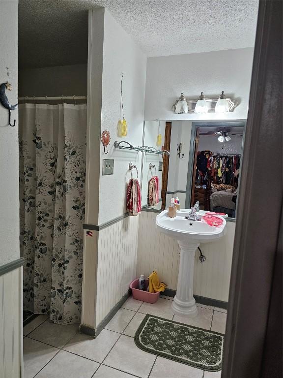 bathroom featuring tile patterned flooring, ceiling fan, curtained shower, and a textured ceiling