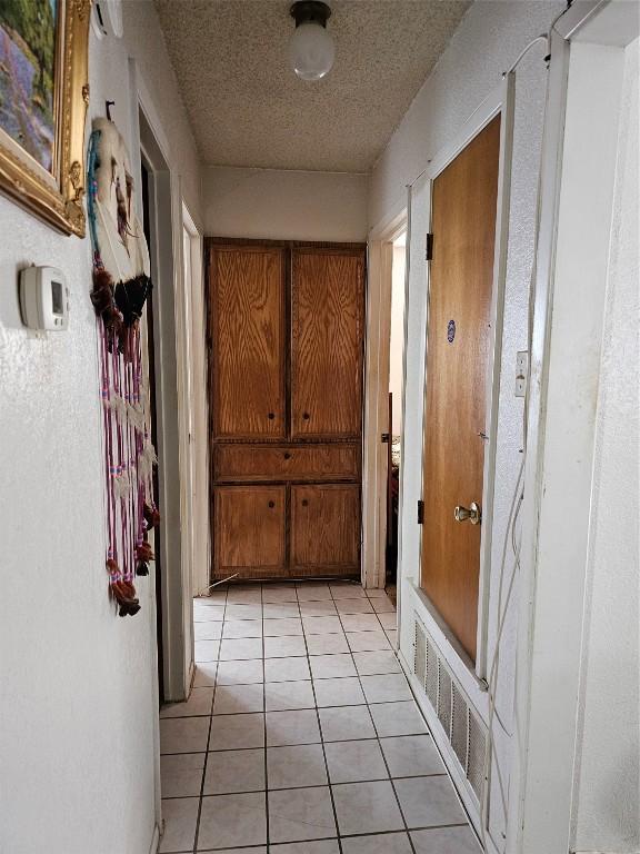 hallway with light tile patterned floors and a textured ceiling