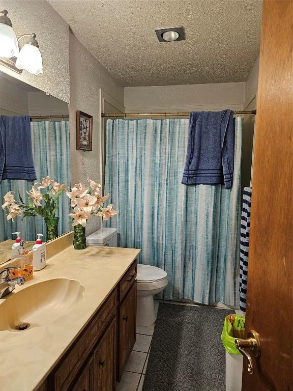 bathroom featuring vanity, a textured ceiling, toilet, and tile patterned flooring