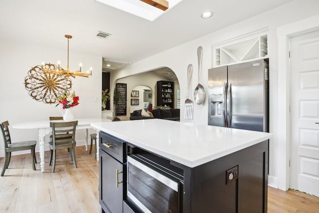 kitchen featuring pendant lighting, light hardwood / wood-style flooring, a chandelier, stainless steel fridge with ice dispenser, and a kitchen island