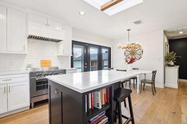 kitchen featuring white cabinets, electric stove, backsplash, and hanging light fixtures