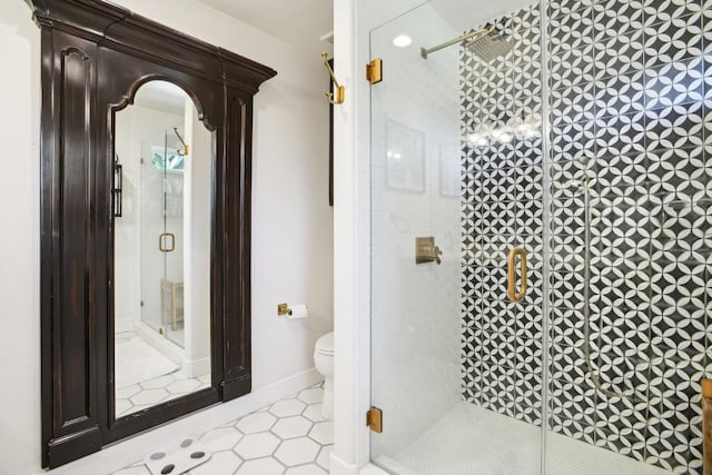 bathroom with tile patterned flooring, toilet, and a shower with shower door