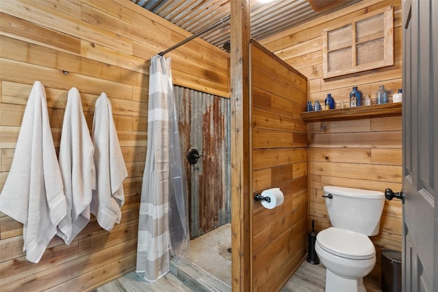 bathroom featuring a shower with curtain, hardwood / wood-style flooring, toilet, and wooden walls