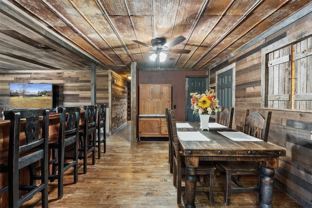 dining space featuring ceiling fan, wood walls, wood-type flooring, and wood ceiling