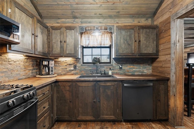 kitchen featuring sink, butcher block countertops, lofted ceiling, dark brown cabinets, and appliances with stainless steel finishes