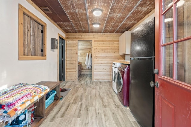 clothes washing area with cabinets, wooden walls, light hardwood / wood-style flooring, wooden ceiling, and washing machine and dryer