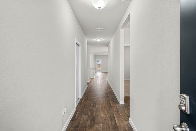 hallway featuring dark wood-style floors, visible vents, and baseboards