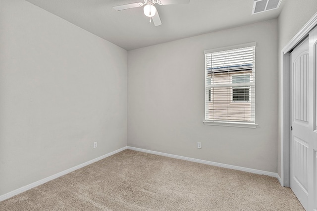 unfurnished room featuring baseboards, a ceiling fan, visible vents, and light colored carpet