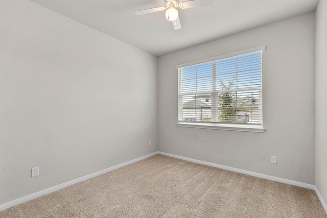 spare room featuring carpet floors, a ceiling fan, and baseboards