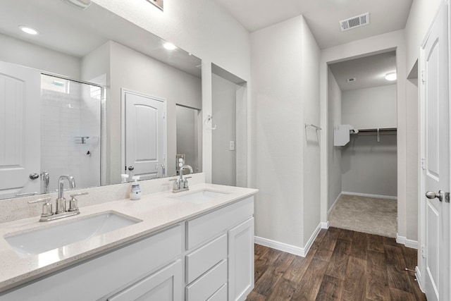 full bathroom with a shower stall, visible vents, a walk in closet, and a sink