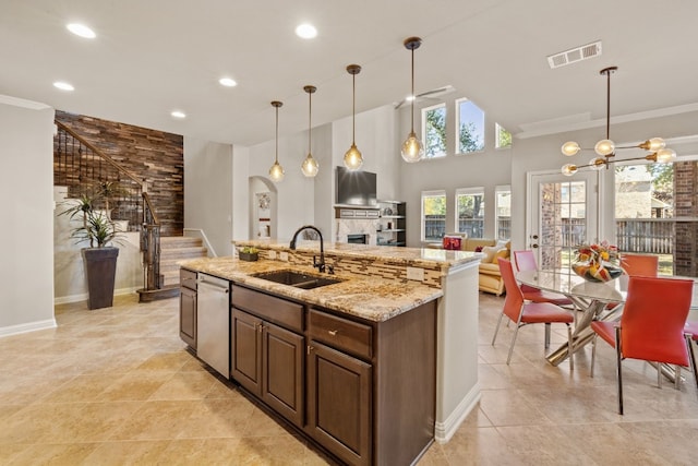 kitchen featuring pendant lighting, sink, stainless steel dishwasher, ornamental molding, and light stone counters