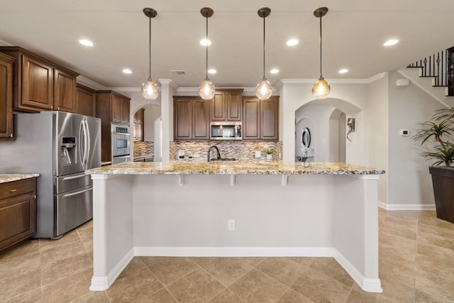 kitchen featuring a breakfast bar area, decorative backsplash, pendant lighting, and stainless steel appliances