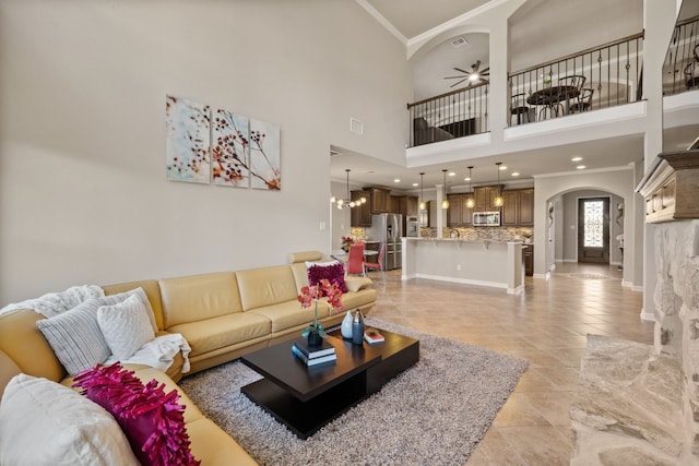 living room with ceiling fan with notable chandelier, ornamental molding, and a towering ceiling