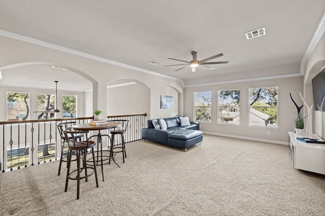 living room with carpet flooring, ceiling fan, a healthy amount of sunlight, and ornamental molding