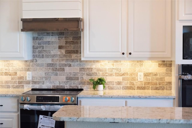 kitchen featuring light stone counters, white cabinetry, and high end stainless steel range oven