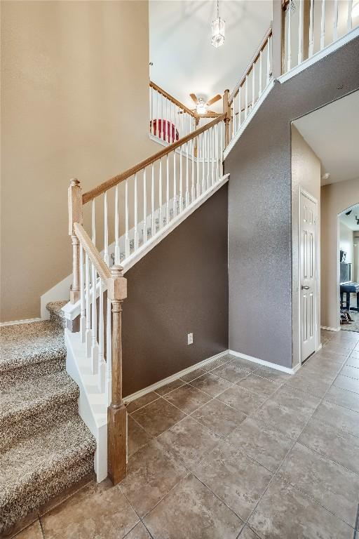 stairway with a towering ceiling and tile patterned flooring