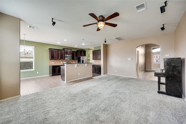 unfurnished living room featuring light carpet and ceiling fan with notable chandelier