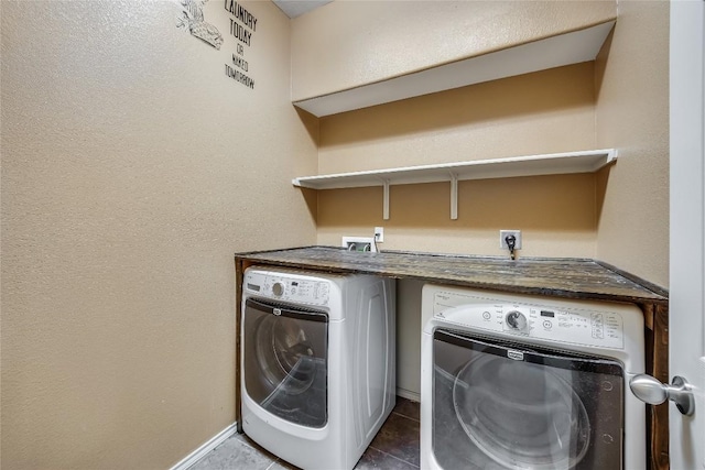 laundry room with washer and clothes dryer and dark tile patterned floors