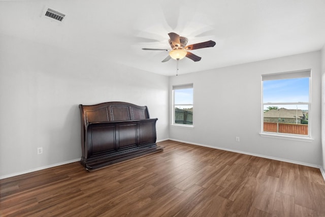 bedroom featuring ceiling fan, dark hardwood / wood-style flooring, and multiple windows