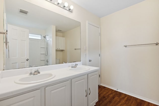 bathroom featuring hardwood / wood-style floors, vanity, toilet, and a shower