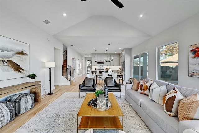 living room featuring light wood-type flooring, vaulted ceiling, and ceiling fan