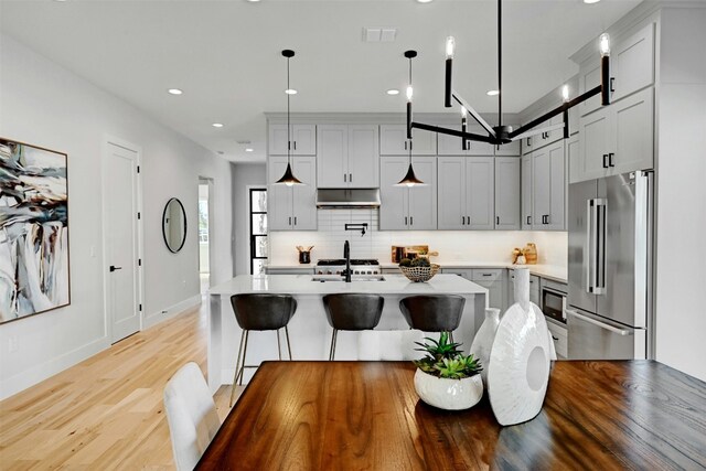 kitchen with decorative backsplash, hanging light fixtures, high quality fridge, and built in microwave