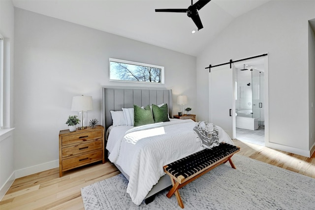 bedroom featuring ensuite bath, ceiling fan, a barn door, lofted ceiling, and hardwood / wood-style flooring