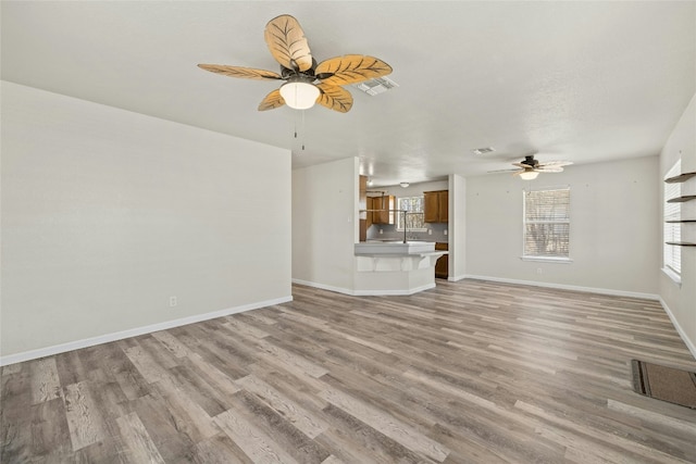 unfurnished living room with ceiling fan, a healthy amount of sunlight, and light wood-type flooring