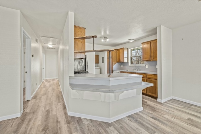 kitchen featuring sink, a textured ceiling, washer / clothes dryer, and light hardwood / wood-style flooring