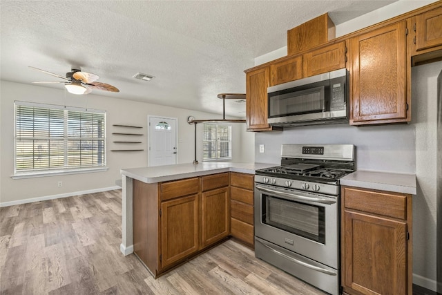 kitchen featuring kitchen peninsula, light hardwood / wood-style flooring, a textured ceiling, and appliances with stainless steel finishes