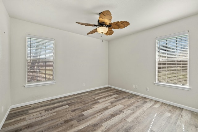 empty room featuring ceiling fan, wood-type flooring, and a wealth of natural light