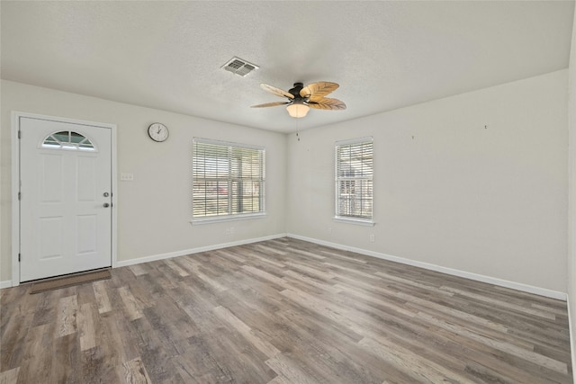 foyer with ceiling fan, a textured ceiling, and light wood-type flooring