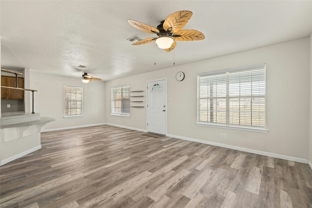 unfurnished living room featuring ceiling fan, light wood-type flooring, and a textured ceiling