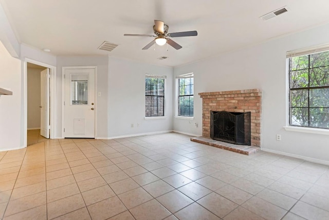 unfurnished living room featuring ceiling fan, light tile patterned floors, ornamental molding, and a brick fireplace