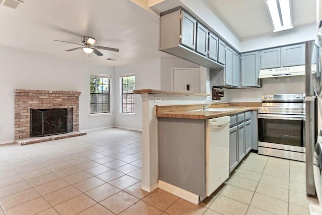 kitchen featuring ceiling fan, dishwasher, light tile patterned floors, wood counters, and stainless steel stove