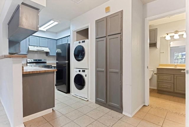 kitchen with wood counters, black refrigerator, stacked washing maching and dryer, stainless steel electric range, and light tile patterned flooring