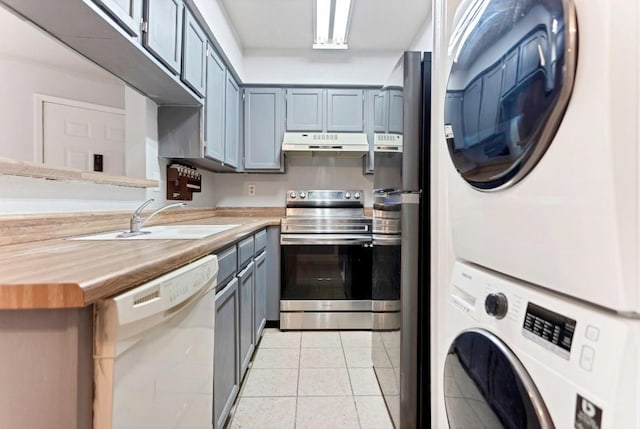 kitchen with stainless steel range with electric stovetop, stacked washer and clothes dryer, white dishwasher, sink, and butcher block countertops