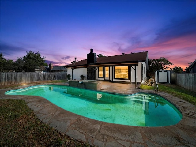 pool at dusk featuring a storage unit and a patio area