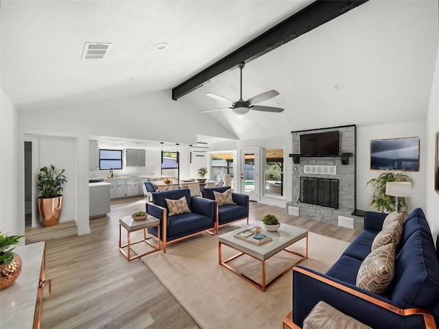 living room featuring a fireplace, vaulted ceiling with beams, light hardwood / wood-style flooring, and ceiling fan