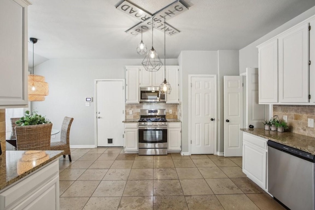 kitchen with dark stone countertops, pendant lighting, white cabinets, and stainless steel appliances