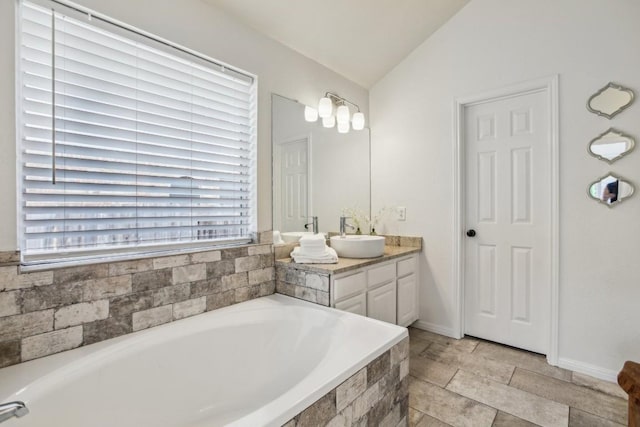 bathroom with lofted ceiling, vanity, and a relaxing tiled tub